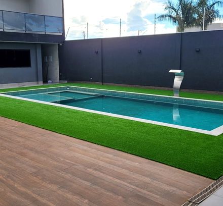 mesma área de piscina com faixa de grama sintética contornando a borda e deck de madeira